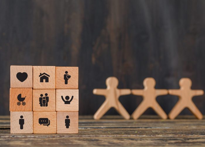 Family concept with icons on wooden cubes, human figures on wooden background side view.